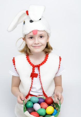 Girl in rabbit costume with a basket of Easter eggs on a white backgroundの写真素材