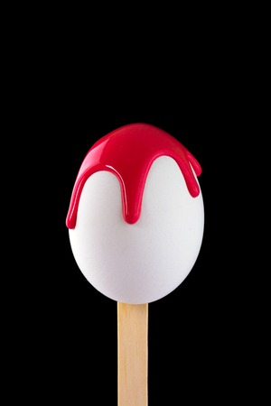 White egg on a wooden stick drenched colorsの写真素材