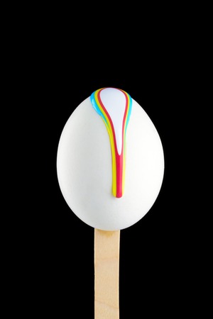 White egg on a wooden stick drenched colorsの写真素材