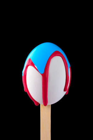 White egg on a wooden stick drenched colorsの写真素材
