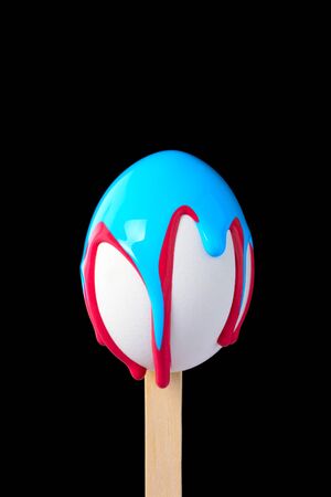 White egg on a wooden stick drenched colorsの写真素材