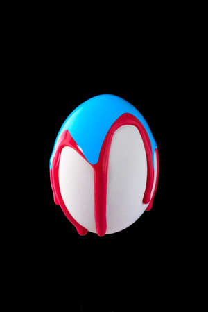 White egg drenched colors on a black backgroundの写真素材