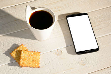 A woman sitting at a white wooden table and pay for purchases via smartphoneの写真素材
