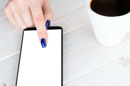 A woman sitting at a white wooden table and pay for purchases via smartphoneの写真素材