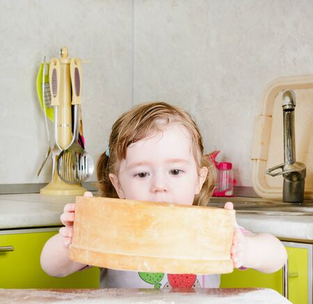 Little girl sifts the flour for the doughの写真素材