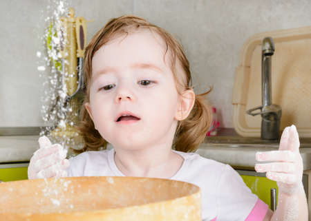 Little girl sifts the flour for the doughの写真素材
