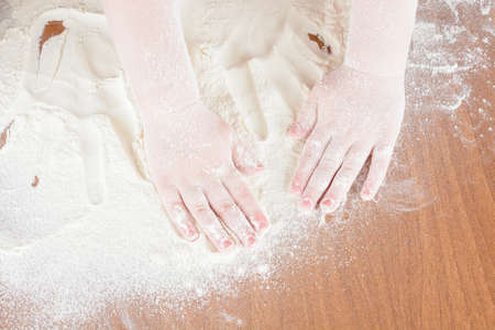 Children's hands on the flour on the tableの写真素材