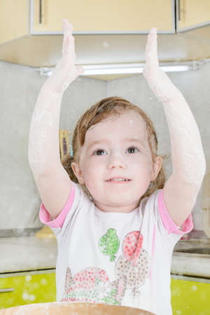 Little girl sifts the flour for the doughの写真素材