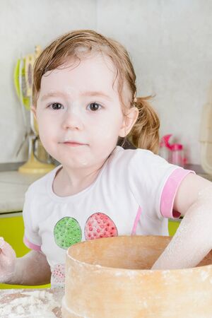 Little girl sifts the flour for the doughの写真素材