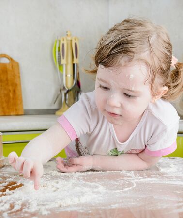 Little girl sifts the flour for the doughの写真素材