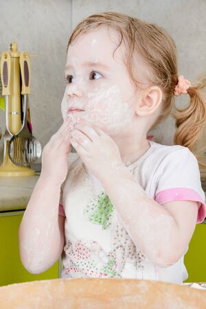 Little girl sifts the flour for the doughの写真素材
