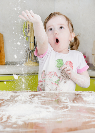 Little girl sifts the flour for the doughの写真素材
