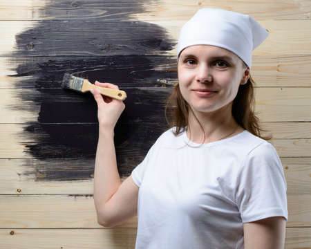 Woman painter paint brush wooden wall in blackの写真素材