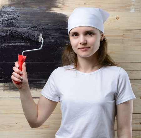 Woman painter paint roller wooden wall in blackの写真素材