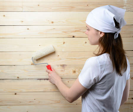 Woman painter with roller stands at wooden wallの写真素材