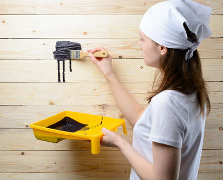 Woman painter paint brush wooden wall in blackの写真素材