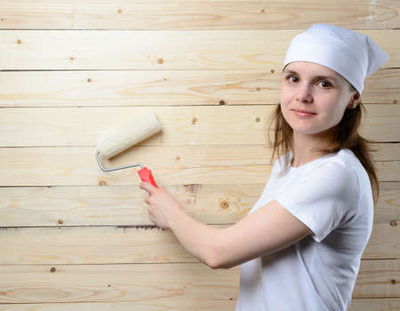 Woman painter with roller stands at wooden wallの写真素材