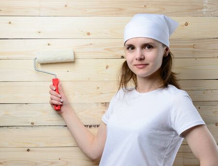 Woman painter with roller stands at wooden wallの写真素材
