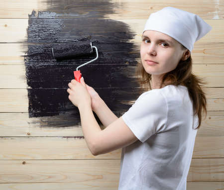 Woman painter paint roller wooden wall in blackの写真素材