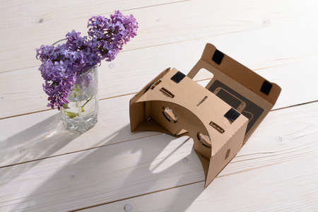 Lilac Bouquet and cardboard VR glasses on a white wooden tableの写真素材