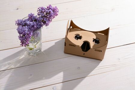 Lilac Bouquet and cardboard VR glasses on a white wooden tableの写真素材