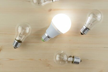 Glowing LED lamp including incandescent lamps on a wooden table
