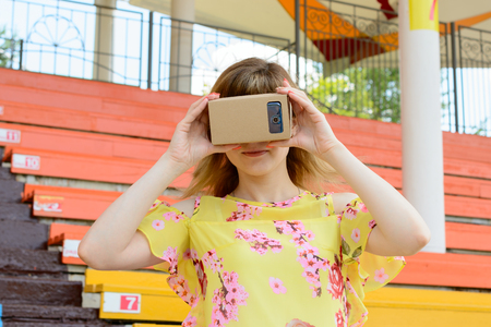 Young woman looking into a virtual reality glasses at the city stadiumの写真素材