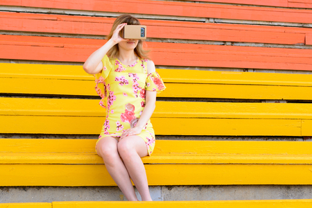 Young woman looking into a virtual reality glasses at the city stadiumの写真素材