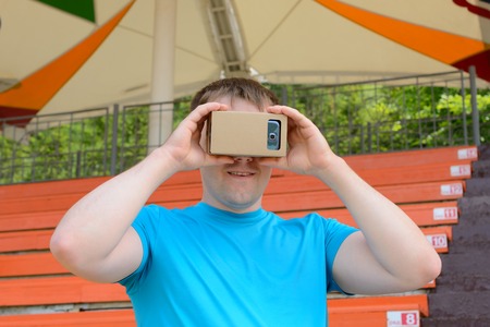 Young man looking into a virtual reality glasses at the city stadiumの写真素材