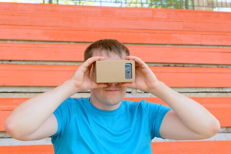 Young man looking into a virtual reality glasses at the city stadiumの写真素材