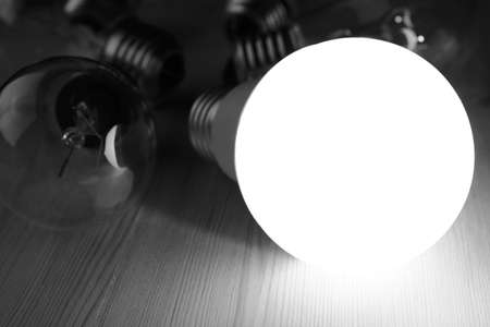 Glowing LED lamp including incandescent lamps on a wooden table