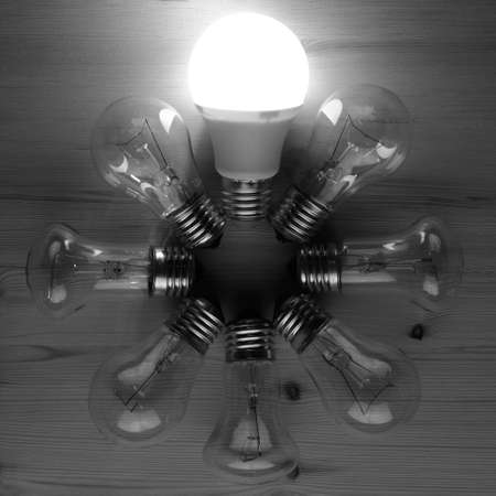 Glowing LED lamp including incandescent lamps on a wooden tableの写真素材