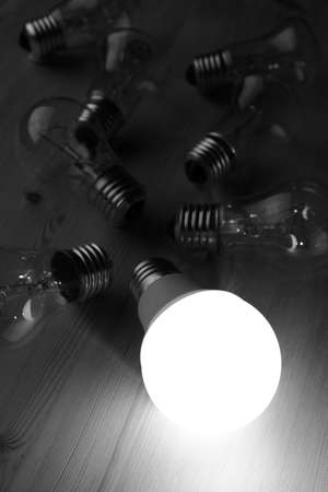 Glowing LED lamp including incandescent lamps on a wooden tableの写真素材