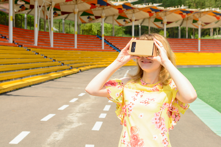 Young woman looking into a virtual reality glasses at the city stadiumの写真素材