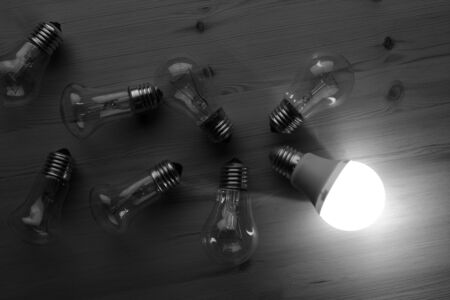 Glowing LED lamp including incandescent lamps on a wooden tableの写真素材