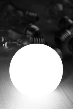 Glowing LED lamp including incandescent lamps on a wooden tableの写真素材