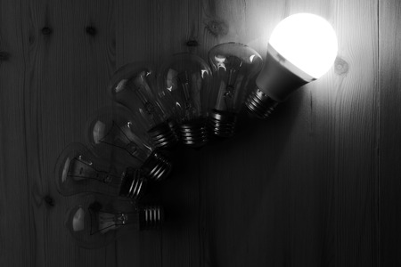 Glowing LED lamp including incandescent lamps on a wooden table, black and white photographyの写真素材