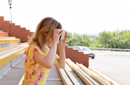 Young woman looking into a virtual reality glasses at the city stadiumの写真素材