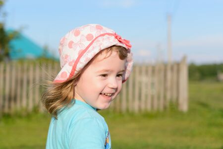 Little girl smiling and walking in the street in the village in summerの写真素材