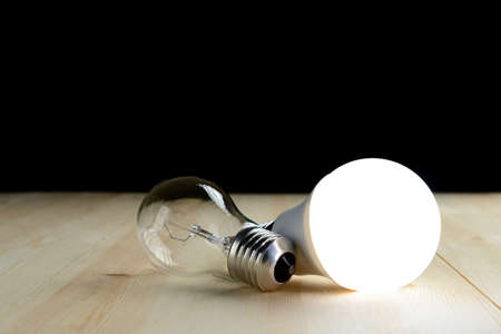 LED lamp and an incandescent lamp lie on a wooden tableの写真素材