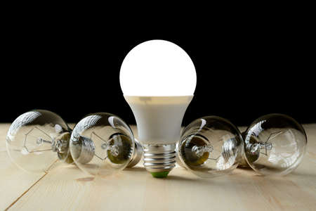 LED lamp standing on a wooden table, near an incandescent lamp lieの写真素材