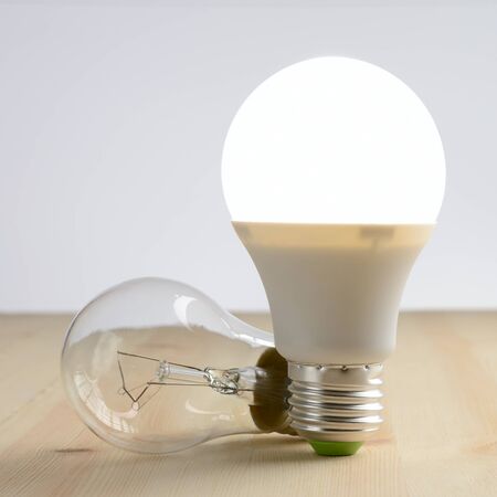 LED lamp standing on a wooden table, near an incandescent lamp lieの写真素材