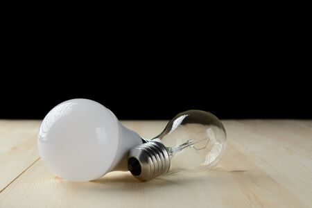 LED lamp and an incandescent lamp lie on a wooden tableの写真素材