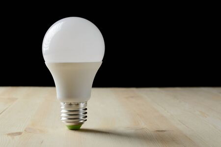 LED lamp standing on a wooden table on a black backgroundの写真素材