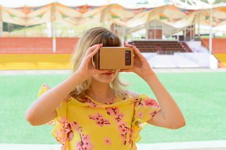 Young woman having fun with virtual reality glasses at the city stadiumの写真素材