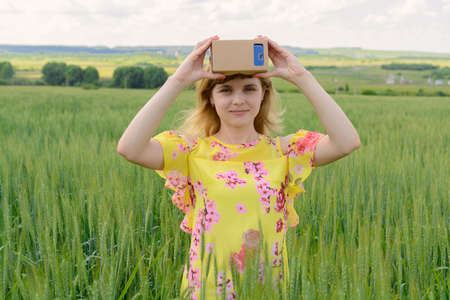 Young woman standing in a field and looks into a virtual reality glassesの写真素材
