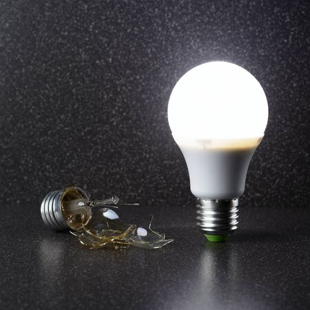 LED lamp stands next to a broken incandescent lampの写真素材