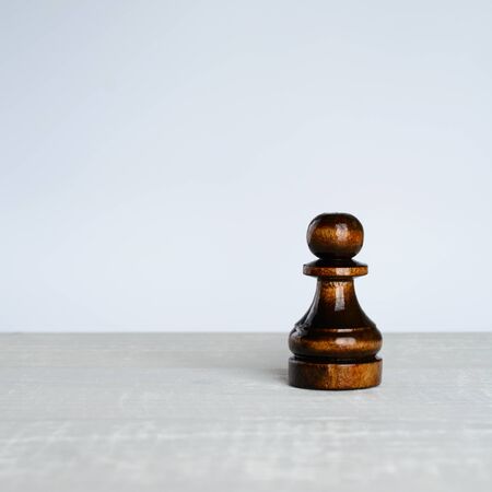 Black pawn on a white table on white backgroundの写真素材
