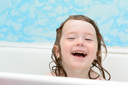 Little girl playing and laughing in the bathroomの写真素材