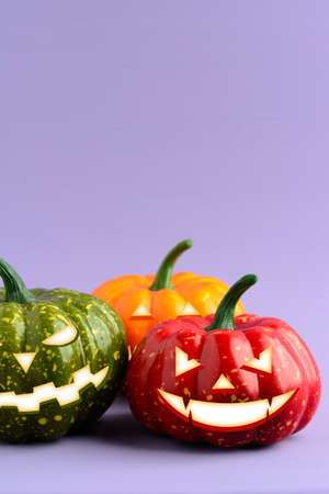 Three Halloween pumpkin with scary face on a purple backgroundの写真素材